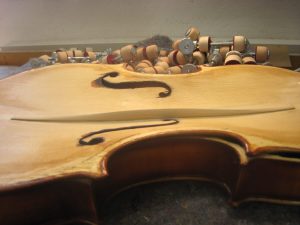 Detailaufnahme eines Streichinstruments mit Schallloch und Werkstatthintergrund.