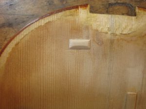 Detailaufnahme eines reparierten Holz-Instrumentes mit sichtbaren Rissflicken und Maserung.