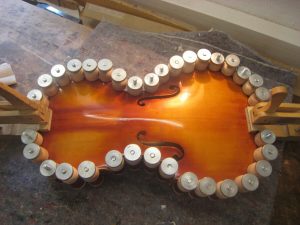 Restaurierte Geigenoberfläche mit Klammern zur Formgebung und Schwingungserhalt.